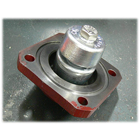 Flanged bearing with red mounting flange and central shaft secured by a nut on a work surface.