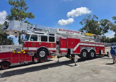 Bloomington Fire Department ladder truck parked on a street with an extended ladder against a blue sky.