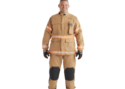 Firefighter in tan turnout gear with reflective orange stripes, standing and smiling.