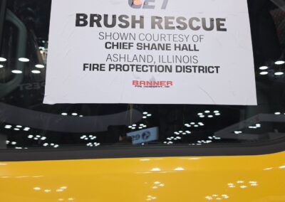 Sign on a yellow vehicle reading 'GET BRUSH RESCUE' with attribution to Chief Shane Hall and the Ashland, Illinois Fire Protection District.