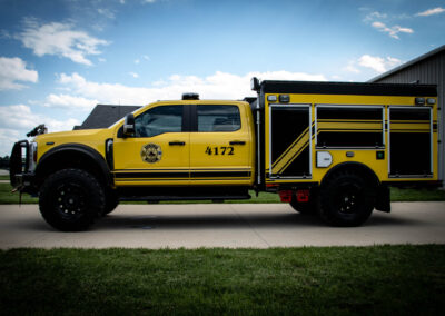 Yellow fire rescue truck parked beside a building on a sunny day, side view showing its emergency equipment and the number 4172 on the door.