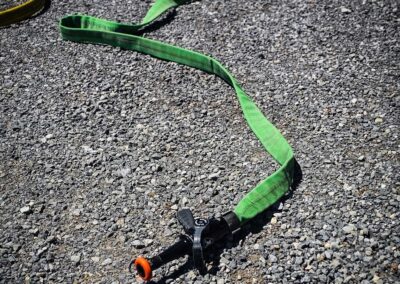 Green and yellow resistance bands laid out on a gravel surface with a black exercise handle in the foreground.