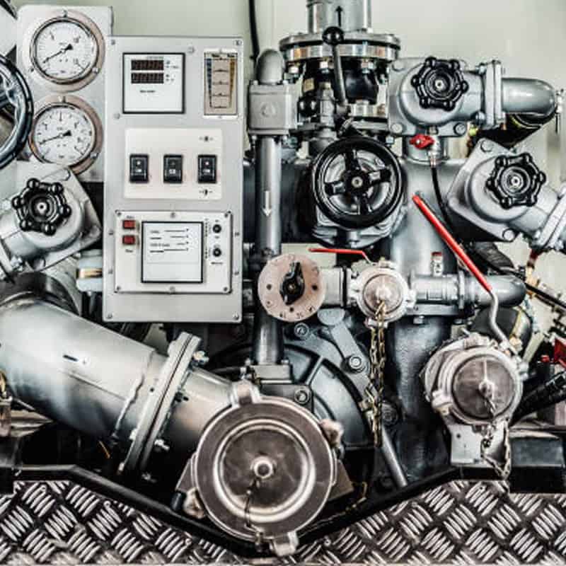 Industrial machinery with gauges, dials, pipes, and control panel in a mechanical room