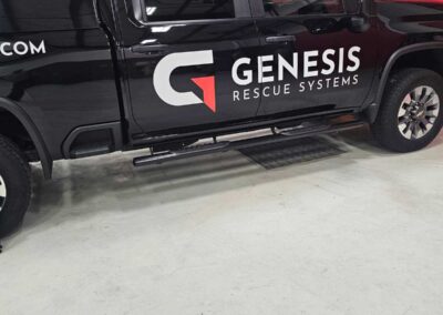 Black Genesis Rescue Systems pickup truck parked in a workshop, logo visible on the door