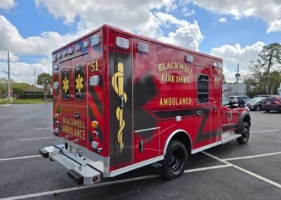 Red Blackwell Fire Department ambulance parked in a lot, red with gold lettering and a medical emblem on the side.