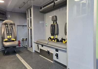 Interior of an ambulance with a patient stretcher and seating along the wall, ready for transport