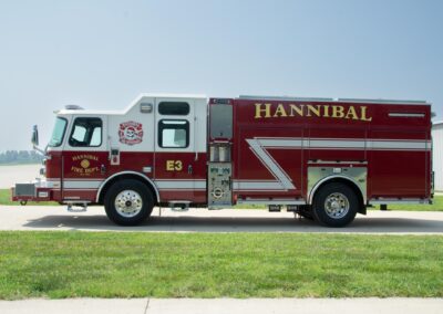 Red and white fire engine labeled Hannibal Fire Dept, parked on a sunny day with a clear blue sky.