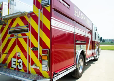 Red fire truck with yellow-and-red chevron rear, ladders and equipment compartments visible in a parking lot
