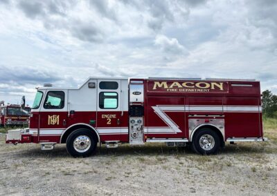 Front-and-side view of a red Macon Fire Department engine labeled Engine 2, parked on a gravel lot under a cloudy sky.