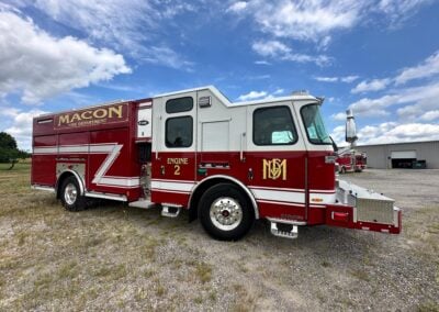 Red Macon Fire Department engine parked on a gravel lot under a blue sky with clouds, showing 'Engine 2' markings and chrome details