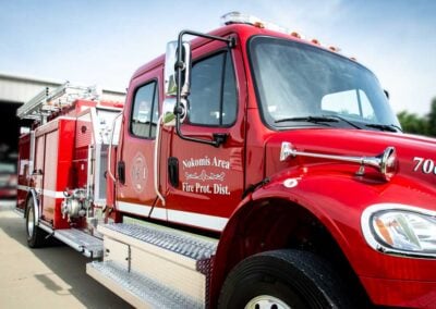Red fire engine parked with ladder on top and 'Nokomis Area Fire Prot. Dist.' on the door, ready for action.