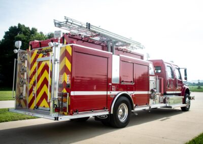 Red fire truck with a long ladder on top, parked on a sunny day.