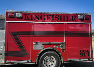 Red fire truck side with large 'KINGFISHER' lettering, diamond-plate trim, and emergency lights above the panel.