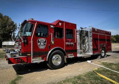 Red fire engine parked on a sunny day with chrome detailing and a Kingfisher Fire Rescue emblem on the door