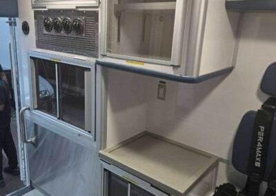 Interior of a modern train galley with stainless steel appliances, including an oven and storage cabinets, and blue seating along the wall.
