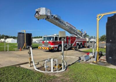 Fire truck with an extended ladder labeled Bloomington Fire Dept, and crew on the ladder during a training or drill in a parking lot.