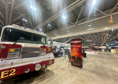 Red fire engine on display at a convention hall with a Banner Fire banner nearby indicating apparatus and service offerings