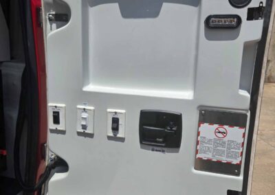 Interior of a vehicle door panel featuring window controls, door latch, and a circular speaker with a warning sticker on the lower right side.