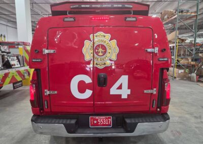 Rear view of a red fire department vehicle in a garage, displaying the Oklahoma City Fire Department emblem on the back doors with a large white tail number.