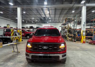 Red Ford pickup centered in a spacious indoor warehouse with shelves and equipment in the background.