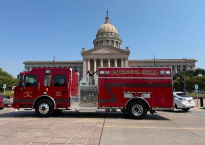 Red fire trucks parked outside a domed neoclassical capitol building on a sunny day.