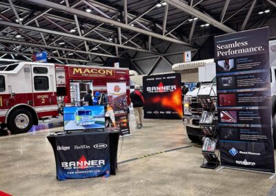 Indoor fire equipment expo booth featuring a red Macon Fire Department engine and Banner Fire Equipment signage with attendees nearby.